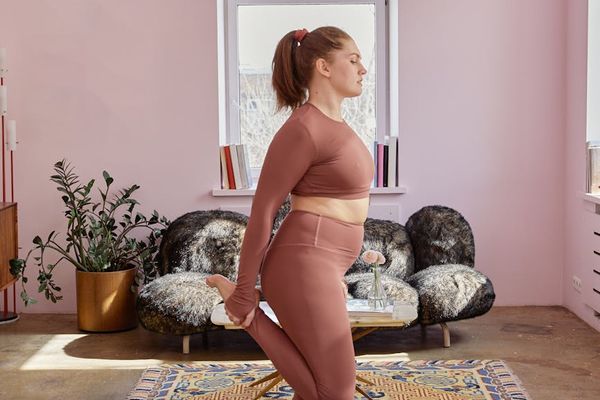 Person in a calm, focused yoga pose in a minimalist setting.