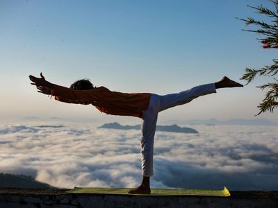 Silhouette of a person in a strong yoga warrior pose against a dark background.